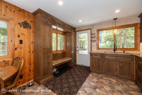 a kitchen with wooden walls and a sink and a table at Breezy Woods - Tobermory Waterfront in Tobermory