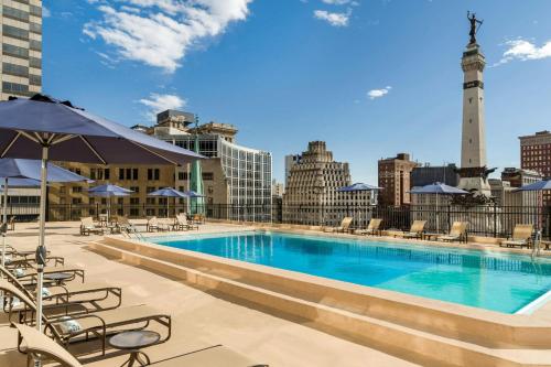 a pool on the roof of a building with chairs and an umbrella at Sheraton Indianapolis City Centre Hotel in Indianapolis