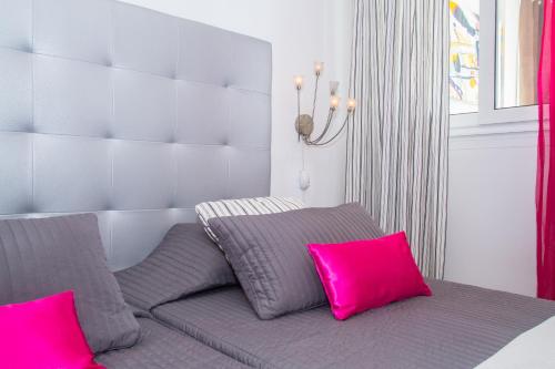 a bed with pink and grey pillows in a room at Alexia Beach in Playa Honda