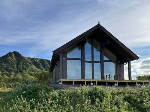 a small wooden building with large windows on a hill at Newly Built Cabin On Andøya With Northern Lights in Bø Andøya