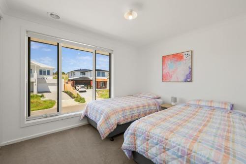 サンレモにあるBay Skies Retreatのベッド2台と窓のある寝室