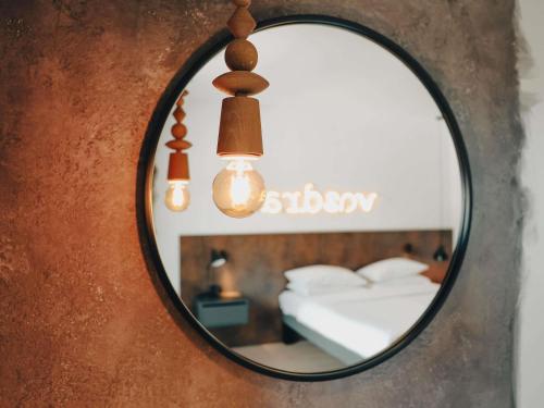 a mirror on a wall with a bed and lights at ibis Styles Sarajevo in Sarajevo