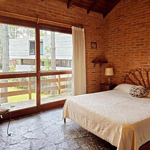 a bedroom with a bed and a large window at Miralejos CARILO PLAYA Y CENTRO in Carilo