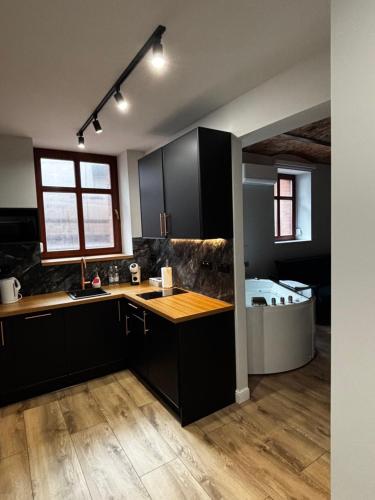 a kitchen with black cabinets and a sink and a tub at Rybaki Sauna & Jacuzzi Apartment in Poznań