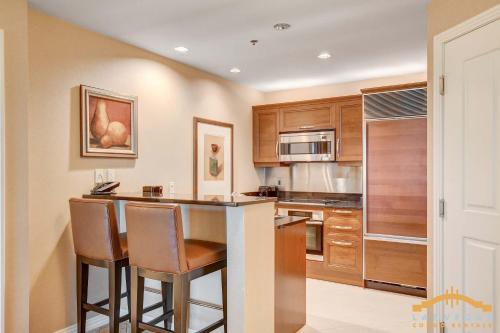 a kitchen with wooden cabinets and a bar with stools at MGM Signature-15-802 1Br 2Ba F1 Pits View Balcony in Las Vegas