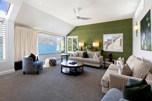 a living room with couches and chairs and a large window at Queenstown House Lakeside in Queenstown