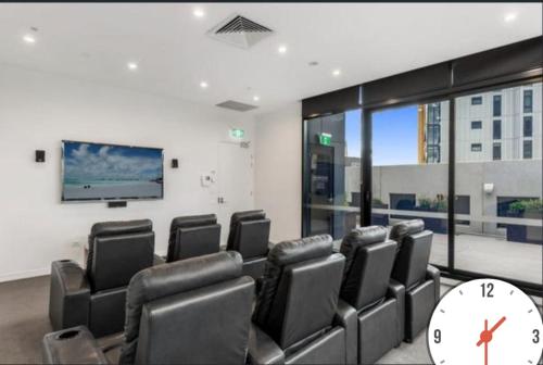 Seffadom apartments Melbourne cbd في ملبورن: غرفة انتظار بها كراسي وساعة كبيرة