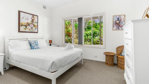 Elizabeth Beach Guest House في Elizabeth Beach: غرفة نوم بيضاء مع سرير ونافذتين