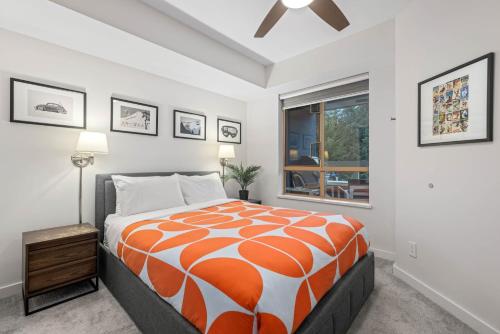 an orange and white bed in a room with a window at 1BR Stylish Condo central Village Location with Private Balcony in Whistler