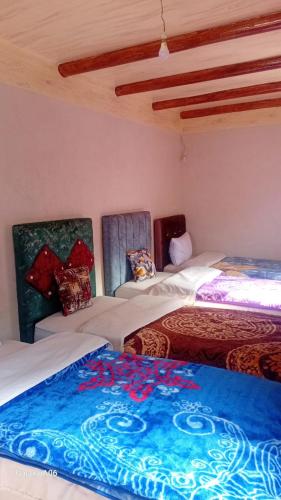 a room with two beds and a blue blanket at Dar Agourzi Café des Epices in Tacheddirt