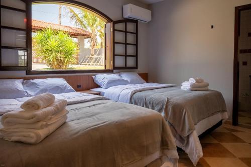 two beds with towels on them in a room with a window at Casa de Campo c 4 Suites AC Wi-Fi em Sao Roque in Mairinque