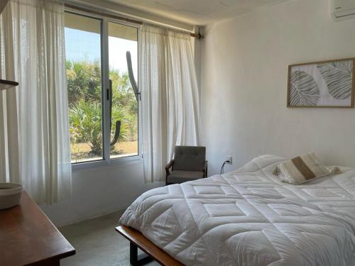 una camera da letto con un letto, una sedia e una finestra di Malanah Casa en la playa y laguna! a El Morro