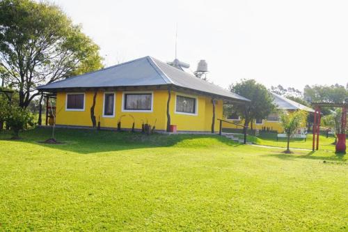 uma pequena casa amarela num campo de relva em Cabañas La Soñada em Chajarí
