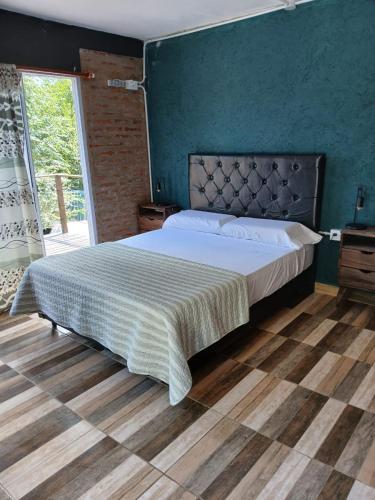 a bedroom with a large bed with a blue wall at Hostel El Refugio de Las Aves in Santa Rosa de Calamuchita