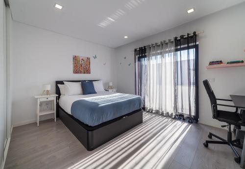 ein Schlafzimmer mit einem Bett, einem Schreibtisch und einem Stuhl in der Unterkunft Modern & Quiet 2BR 2 Baths 4 Balconies & Lift in Ílhavo