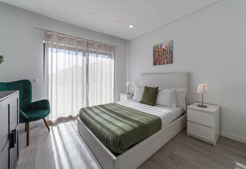ein weißes Schlafzimmer mit einem Bett und einem grünen Stuhl in der Unterkunft Modern & Quiet 2BR 2 Baths 4 Balconies & Lift in Ílhavo