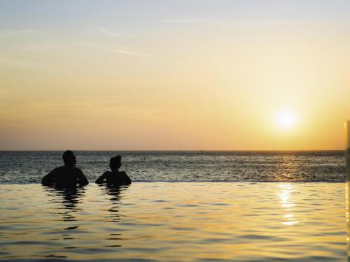two people sitting in the water watching the sunset at Mercure Vung Tau Resort in Vung Tau