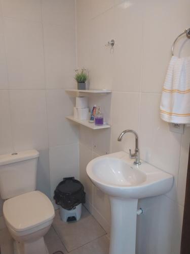 a white bathroom with a toilet and a sink at Villa Hostel in Belém