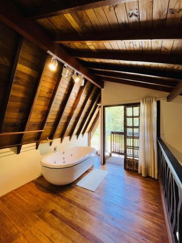 a large bathroom with a tub on a wooden floor at Cabana na Natureza Com Hidro - Baoba Suites in Bombinhas