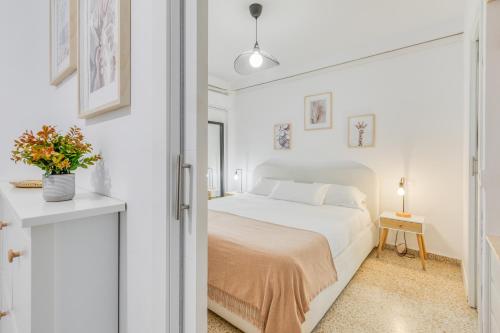 a white bedroom with a bed and a table at Hanami Avenida de España Beach Front - Mountain View in Estepona