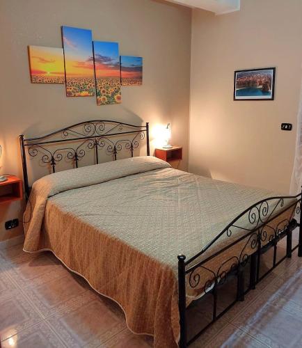 a large bed in a bedroom with paintings on the wall at Villa del Capo in Capo Vaticano