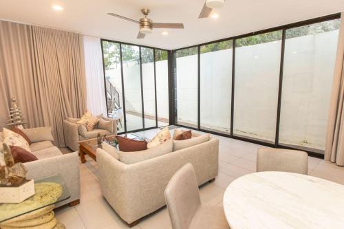 a living room with couches and tables and large windows at Casa Itzae Hotel Boutique in Mérida