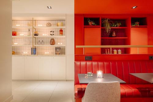 Un comedor con un reservado rojo con una mesa. en Leonardo Eden Hotel Amsterdam City Center, en Ámsterdam