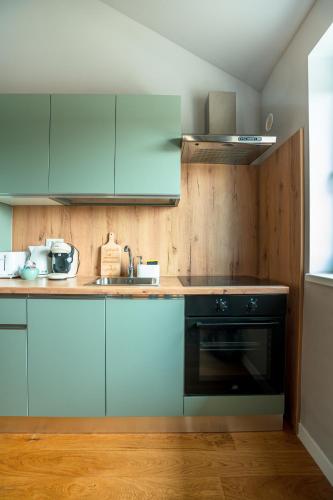 a kitchen with blue cabinets and a black oven at The Nest Beneath the Citadel - 5 min to City Square in Râşnov