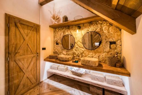 a bathroom with two sinks and a stone wall at Deer Apartment in Lipí