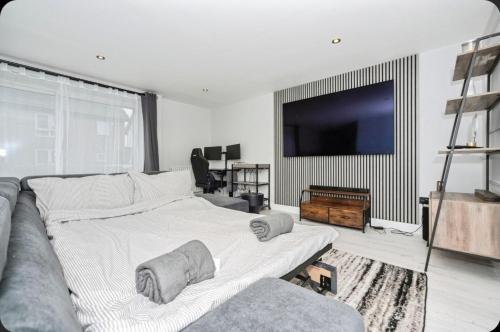 Stunning, Newly Refurbished 1-Bedroom Flat in Gravesend في غريفسيند: غرفة نوم بها سرير كبير وتلفزيون بشاشة مسطحة