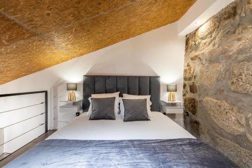 ein Schlafzimmer mit einem großen Bett und einer Steinwand in der Unterkunft Lapa 4 House in Porto