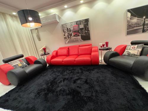a living room with a red couch and two chairs at Stella Heights in El Alamein