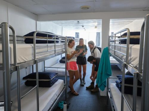 a group of people standing in a room with bunk beds at Attic Backpackers in Auckland
