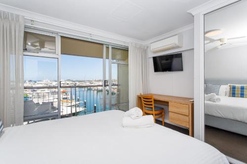 a bedroom with two beds and a desk and a balcony at Sunset Marina Escape Freo-amazing Views & Central in Fremantle