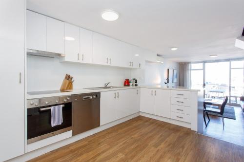 a kitchen with white cabinets and stainless steel appliances at Sunset Marina Escape Freo-amazing Views & Central in Fremantle