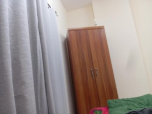 a wooden cabinet in a room with a curtain at Happy living room stay in Sharjah