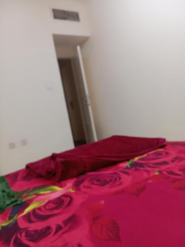 a bed with a pink blanket on top of it at Happy living room stay in Sharjah