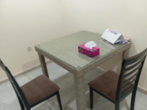 a table with two chairs and a pink box on it at Happy living room stay in Sharjah