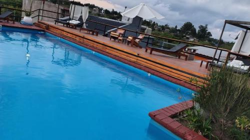 a large blue swimming pool with benches and an umbrella at Del valle cabañas in Tanti
