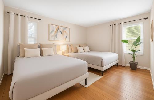 a white bedroom with two beds and a plant at Marina Retreat, Near Beaches&SoFI in Los Angeles