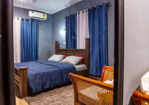a bedroom with a bed and blue curtains at Bluegreen Guest House in Accra