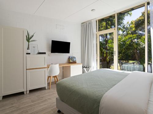 a bedroom with a bed and a desk with a television at Peninsula Beach Motel in Rosebud