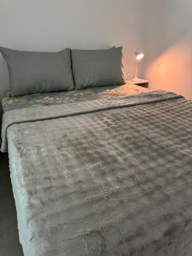 a large bed with a gray comforter on it at Pousada Oito Mares in Arraial do Cabo