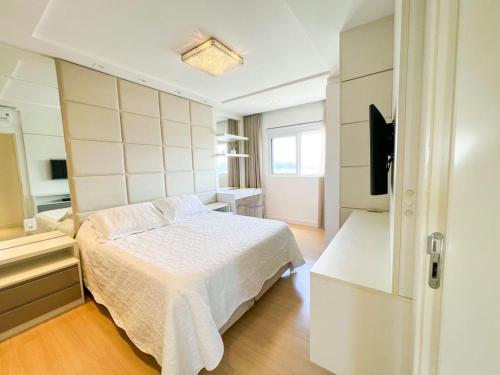 a bedroom with a white bed and a television at Alto Padrão - Balneário Camboriú in Balneário Camboriú