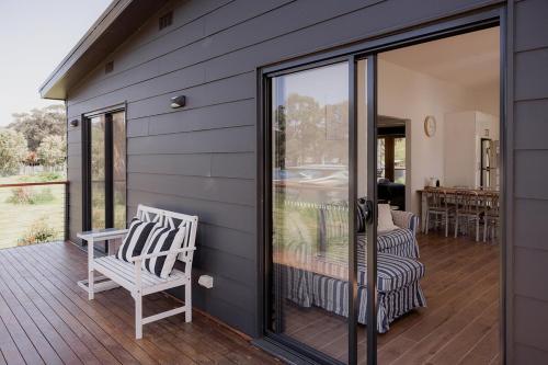 a patio with two chairs and a sliding glass door at The Beach Box at Big Roaring Beach Tasmania in Surveyors Bay