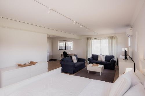 a living room with two blue couches and a tv at The Beach Box at Big Roaring Beach Tasmania in Surveyors Bay