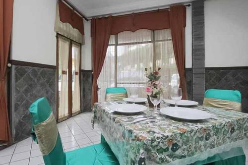 a dining room with a table with plates and chairs at Hotel Lestari Near Lippo Plaza Mall Jember in Jember