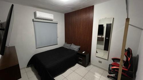 1 dormitorio con cama negra y espejo en Bonita casa de lujo, en Ciudad Obregón