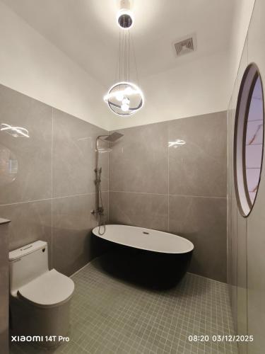 ein Badezimmer mit Badewanne und Toilette in der Unterkunft Biệt Thự 3 Phòng Ngủ A1-03 in Ðức Hòa