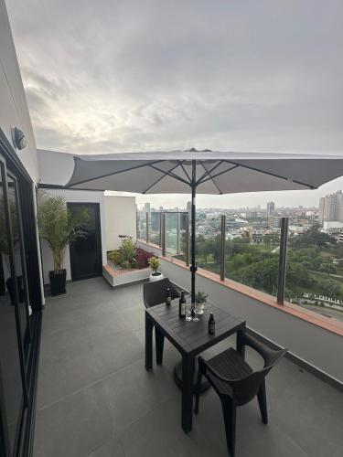 een tafel en stoelen op een balkon met een parasol bij Luxury Duplex on the 15th Floor with Terrace in Lima